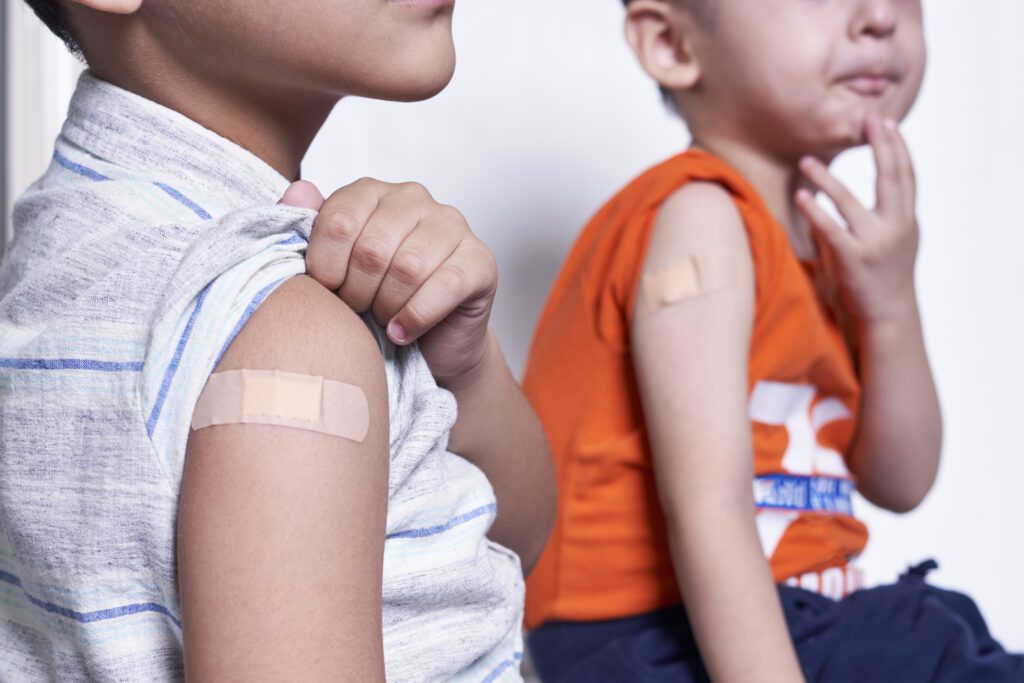 Two boys showing arms with bandages