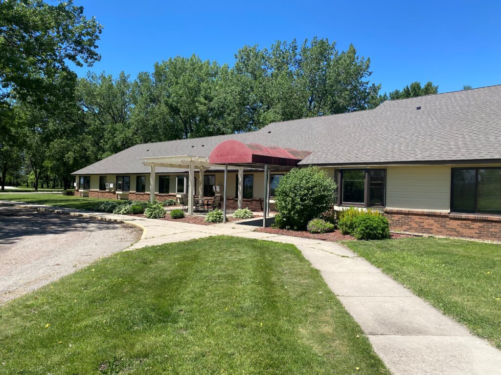 Apartment building with a red canopy and green grass with a blue sky