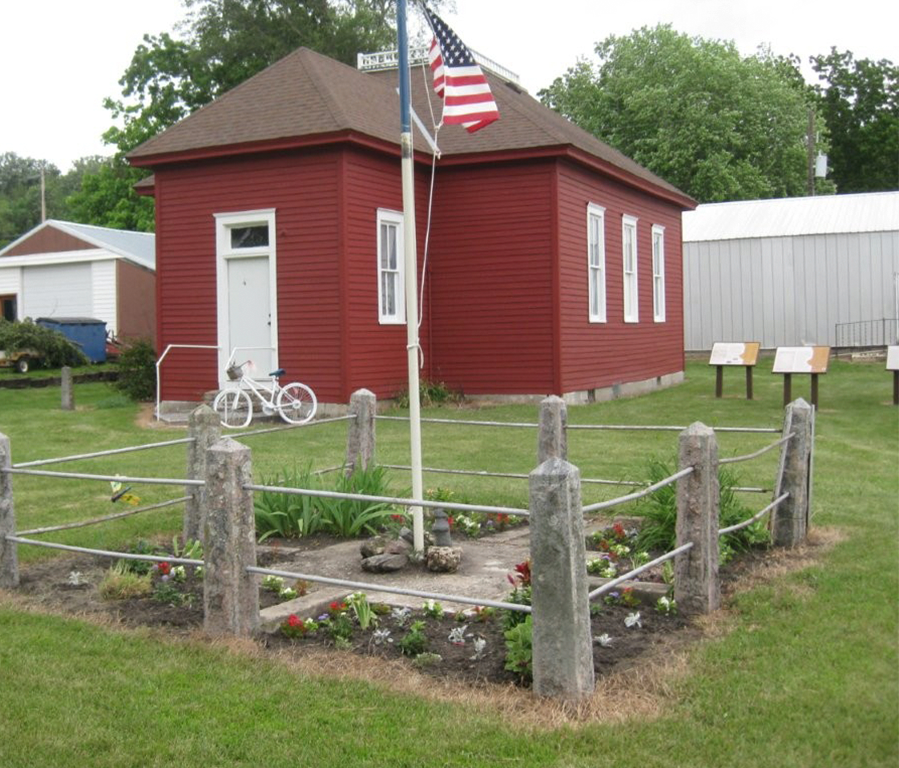 Red museum building with garden and flag in front