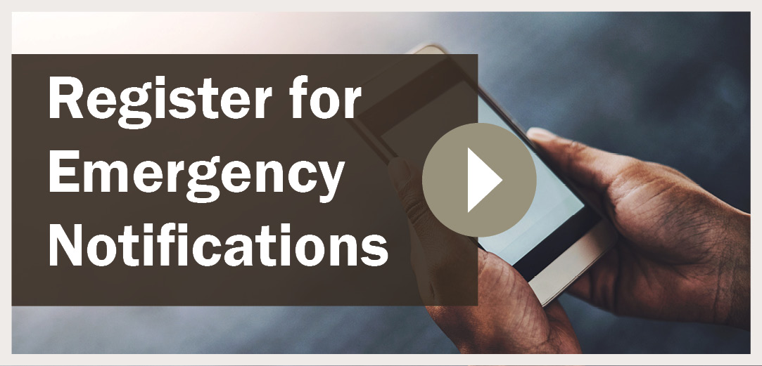 Register for Emergency Notifications message with person holding cellphone in the background